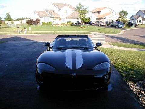 1996 Dodge Viper - A black convertible sports car with racing stripes is parked in a suburban driveway.
