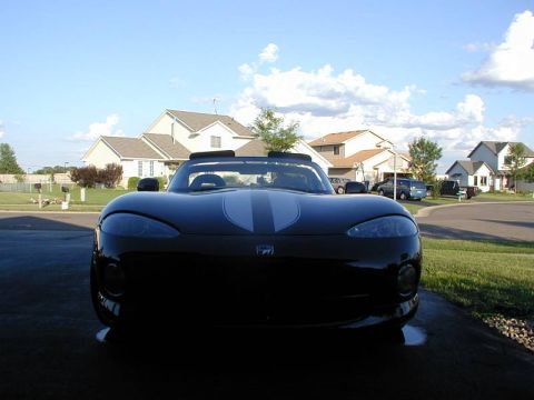 1996 Dodge Viper - A black convertible sports car with silver racing stripes is parked in a driveway on a sunny day.