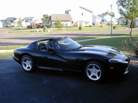1996 Dodge Viper - A black 1996 Dodge Viper convertible is parked on a driveway in front of a suburban house.