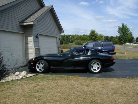 1996 Dodge Viper - A black 1996 Dodge Viper convertible is parked in a driveway next to a house, with another SUV in the background.