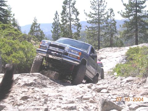 1994 Ford Bronco - Pickup truck tackling a challenging off-road course with steep inclines and large rocks.