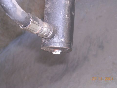 1994 Ford Bronco - Hydraulic cylinder and hose assembly, with a bolt visible at the base of the cylinder.