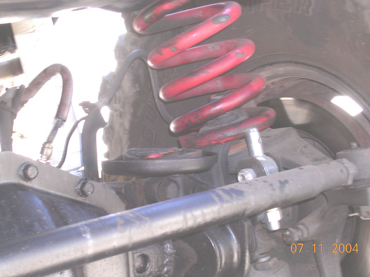 He also seperated the coil from the bucket, and it rested happily stuck between the C and the knuckle.  After replacing the ram, he parked the passenger tire upup on a rock, used a hilft on the drivers tire to lift the body from the tire, and then we could remove the spring.  It was tough to get everything lined up again.