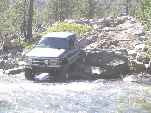 1994 Ford Bronco - A blue pickup truck navigates a challenging rocky stream, with a date stamp of 07.11.2004 visible.