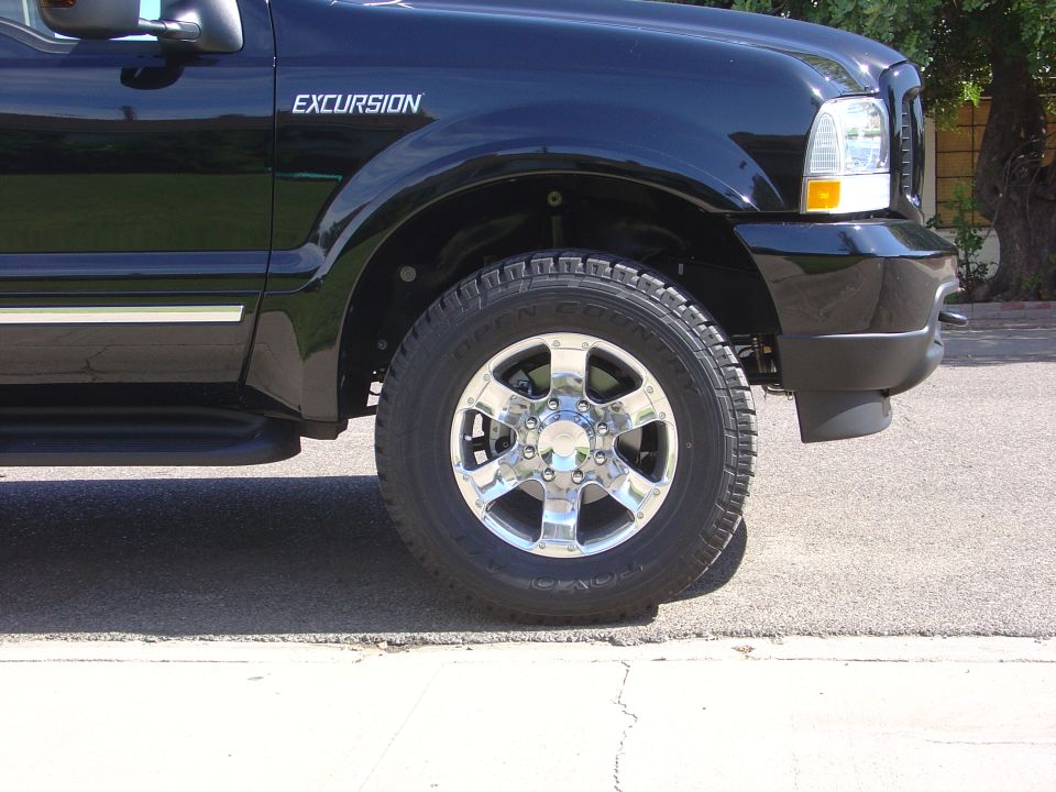 Front fender of a black Ford Excursion with Toyo Open Country tire on chrome 8-lug wheel