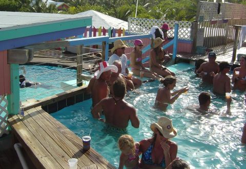 1993 Ford Bronco - A group of people enjoy a sunny day at a resort pool, with tropical foliage visible.