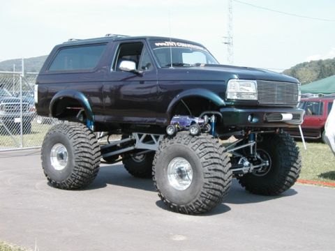 1994 Ford Bronco - This lifted 1994 Ford Bronco features oversized tires and a miniature truck placed on one of its massive wheels.