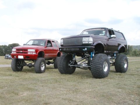 1994 Ford Bronco - A lifted 1994 Ford Bronco is parked next to a red lifted SUV.
