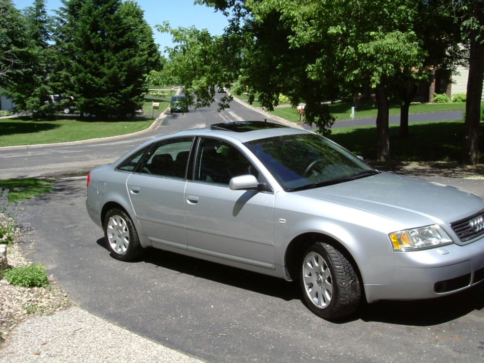 Silver Audi A6 sedan parked in driveway, front three-quarter view with open sunroof