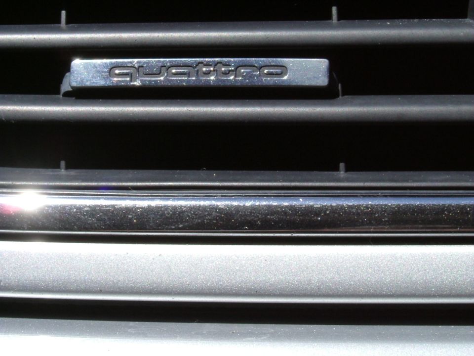 Close-up of silver Audi grille slats with chrome 'quattro' badge