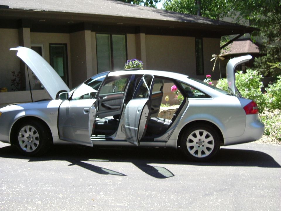 Silver Audi sedan, side view, hood, doors and trunk open in a driveway