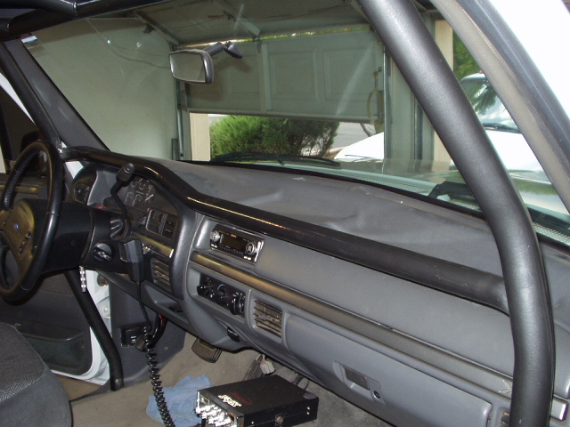 Gray interior dash and steering wheel of a 1990s Ford truck with CB radio on the floor
