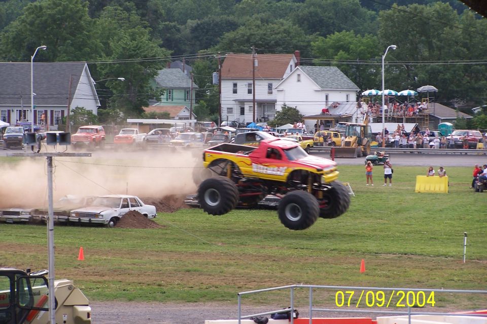 Monster truck mid-air over crushed cars, spectators in background