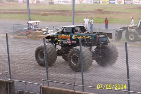 1979 Ford Bronco - Monster truck named 'AVENGER' with flame graphics drives on a dirt track.