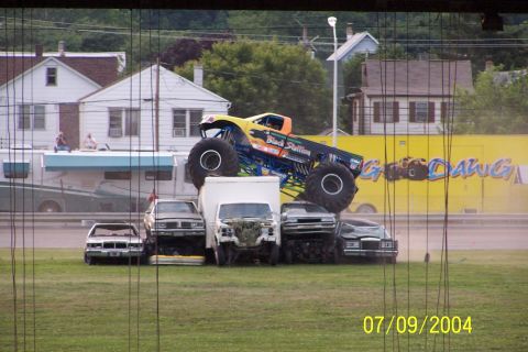 1979 Ford Bronco - A monster truck is shown crushing several cars in an outdoor arena.