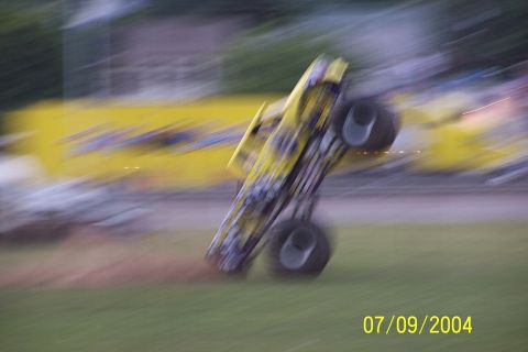 1979 Ford Bronco - Monster truck performing a wheelie on a grassy field, captured with motion blur.