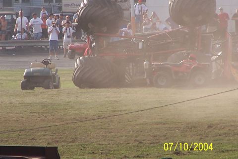 1979 Ford Bronco - A monster truck event with a vehicle overturned on the field, an ATV and golf cart also present.