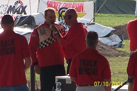 1979 Ford Bronco - Event officials in red shirts stand near a damaged vehicle at an outdoor event.