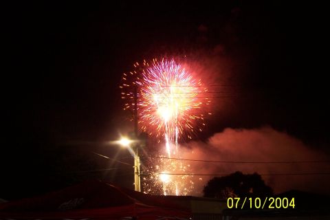 1979 Ford Bronco - A vibrant fireworks display lights up the night sky, with smoke billowing and a street light illuminating the scene below.