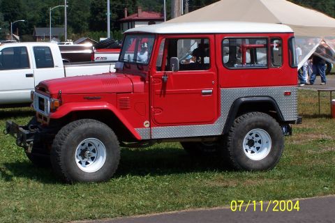 1979 Ford Bronco - A red 1979 Toyota Land Cruiser FJ40 is parked outdoors next to a white pickup truck.