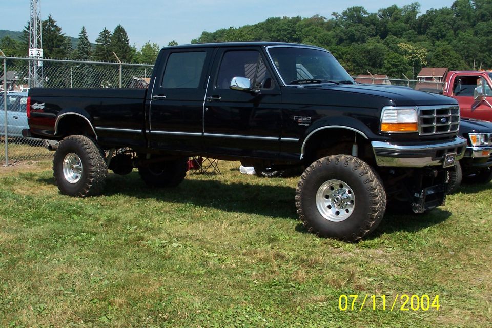 Black Ford F-250 pickup truck with large tires, lifted suspension, and chrome accents