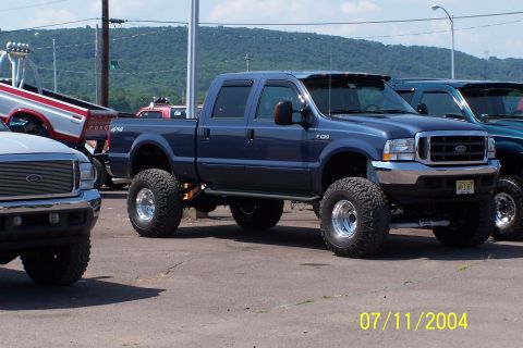 1979 Ford Bronco - A lifted blue Ford F-250 Super Duty pickup truck is parked alongside other vehicles.