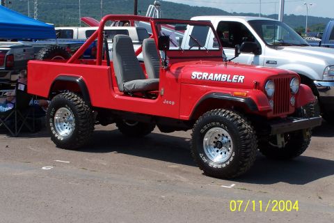 1979 Ford Bronco - This red Jeep CJ-8 Scrambler is parked next to a white pickup truck.