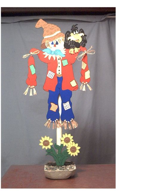 1979 Ford Bronco - A decorative scarecrow figure, complete with a crow companion and sunflowers, stands against a plain backdrop.