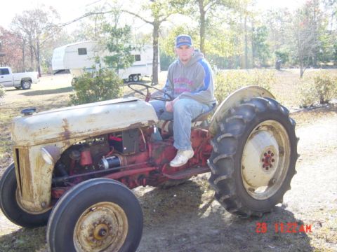 1993 Ford Bronco - A man sits on a weathered tractor in a rural setting.