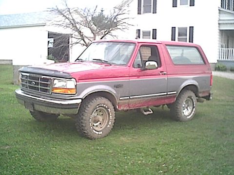 1994 Ford Bronco - This two-tone Ford Bronco is parked on a grassy lawn with a house in the background.