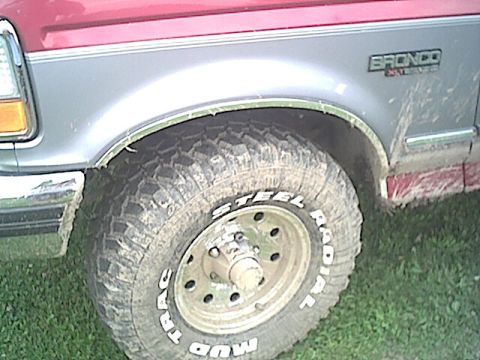 1994 Ford Bronco - The side of a Ford Bronco shows a muddy tire and fender with "Bronco" badging visible.