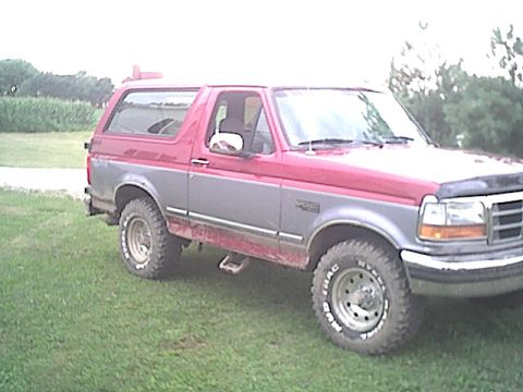 1994 Ford Bronco - This two-tone Ford Bronco is shown from the front three-quarter view, parked on a grassy area.