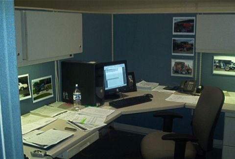 1985 Ford LTD Crown Victoria - A cluttered office cubicle displays framed pictures of various vehicles on the wall.