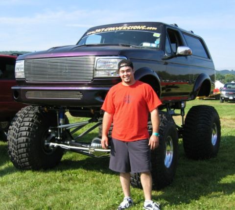 1994 Ford Bronco - Custom lifted Ford Bronco with a man posing in front of it.