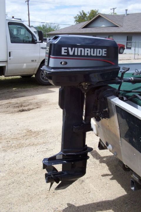 1996 Ford Bronco - An Evinrude outboard motor is attached to the stern of a boat, with a white truck parked nearby.