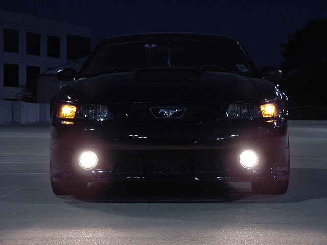 Black Ford Mustang at night, front view with fog lights and amber turn signals illuminated