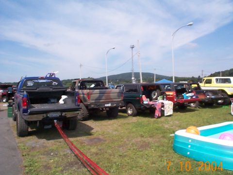 1978 Ford Bronco - Several SUVs and trucks are parked in a grassy area under a blue sky, including a 1978 Ford Bronco.