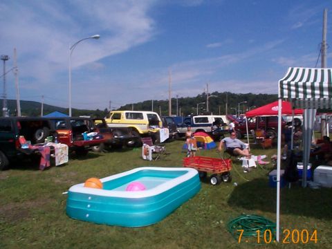 1978 Ford Bronco - An outdoor gathering features multiple SUVs and trucks parked on a grassy field under a blue sky.