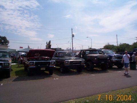 1978 Ford Bronco - A red 1978 Ford Bronco is displayed with its hood open, alongside other trucks at an outdoor event.