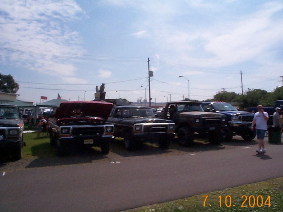 Red 1978 Ford Bronco with hood open, parked in a line of trucks