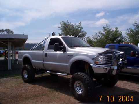 1978 Ford Bronco - Silver Ford F-250 pickup truck with aftermarket modifications, parked outdoors next to another truck.