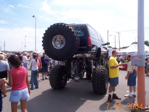 1978 Ford Bronco - A heavily modified Chevrolet SUV is displayed at an outdoor event, drawing attention from onlookers.