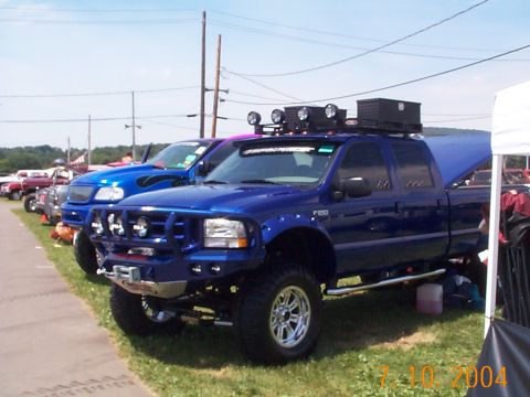 1978 Ford Bronco - A blue Ford F-250 Super Duty truck is parked in a line with other vehicles.