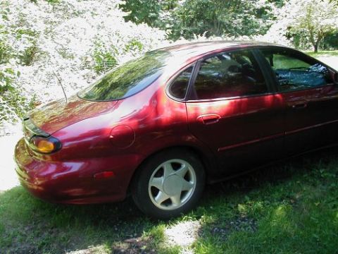 1997 Ford Taurus - Rear view of a red 1997 Ford Taurus sedan parked outdoors on a sunny day.