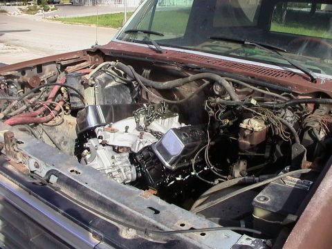 1985 Ford Bronco - Engine bay of a vehicle undergoing an engine swap, a newly installed engine with chrome valve covers.