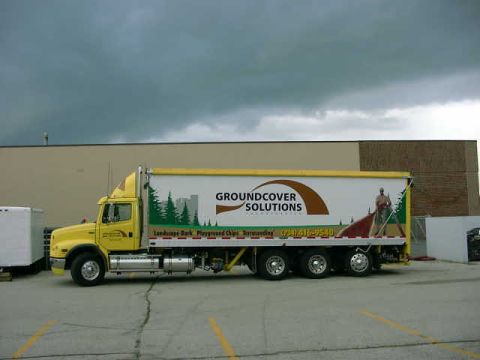 1998 Ford Ranger - A yellow box truck with advertising for Groundcover Solutions is parked in front of a building.