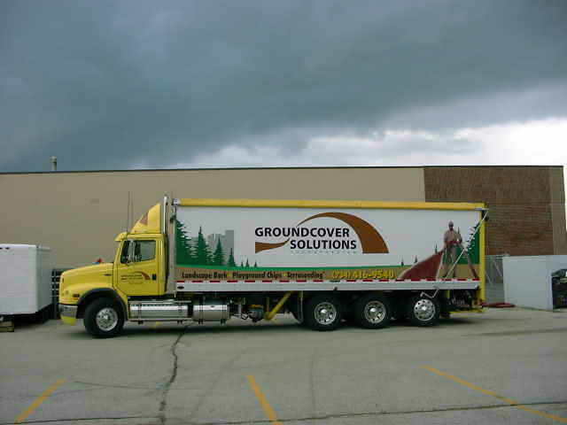 Yellow box truck with "GROUNDCOVER SOLUTIONS" advertisement on the side