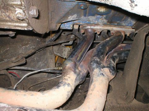1978 Ford Bronco - Close-up view of the exhaust manifold on a 1978 Ford Bronco, showing signs of wear and tear.