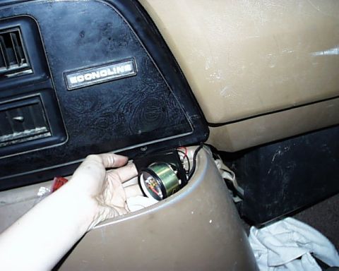 1988 Ford E250 - A gauge is being installed into the dashboard of a vehicle, near an ECONOLINE trim piece.