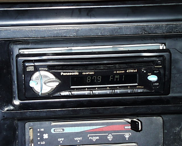 Panasonic CD receiver head unit showing 87.9 FM1 above black HVAC controls